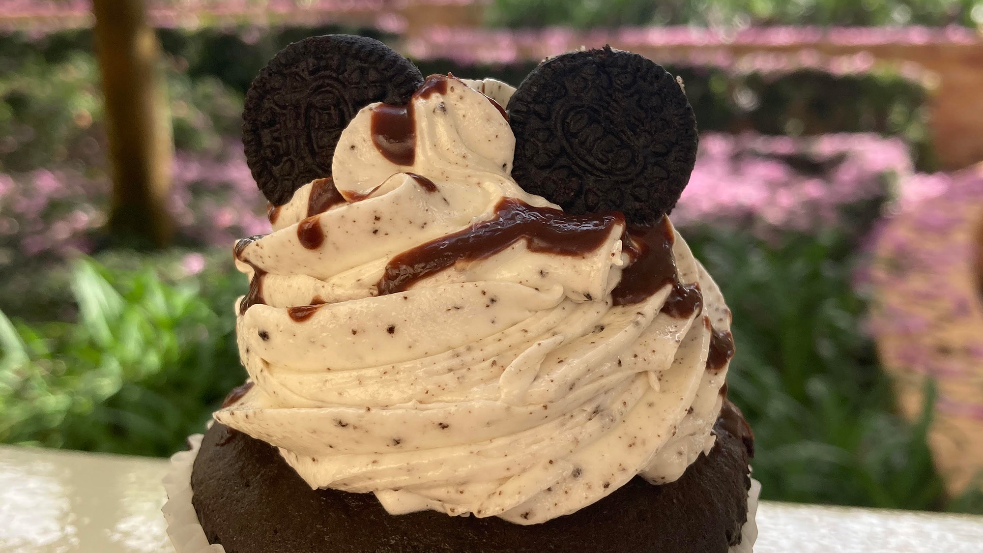 A Mickey cup cake sits atop a trash can before being prepared to be eaten by a Disney stan.