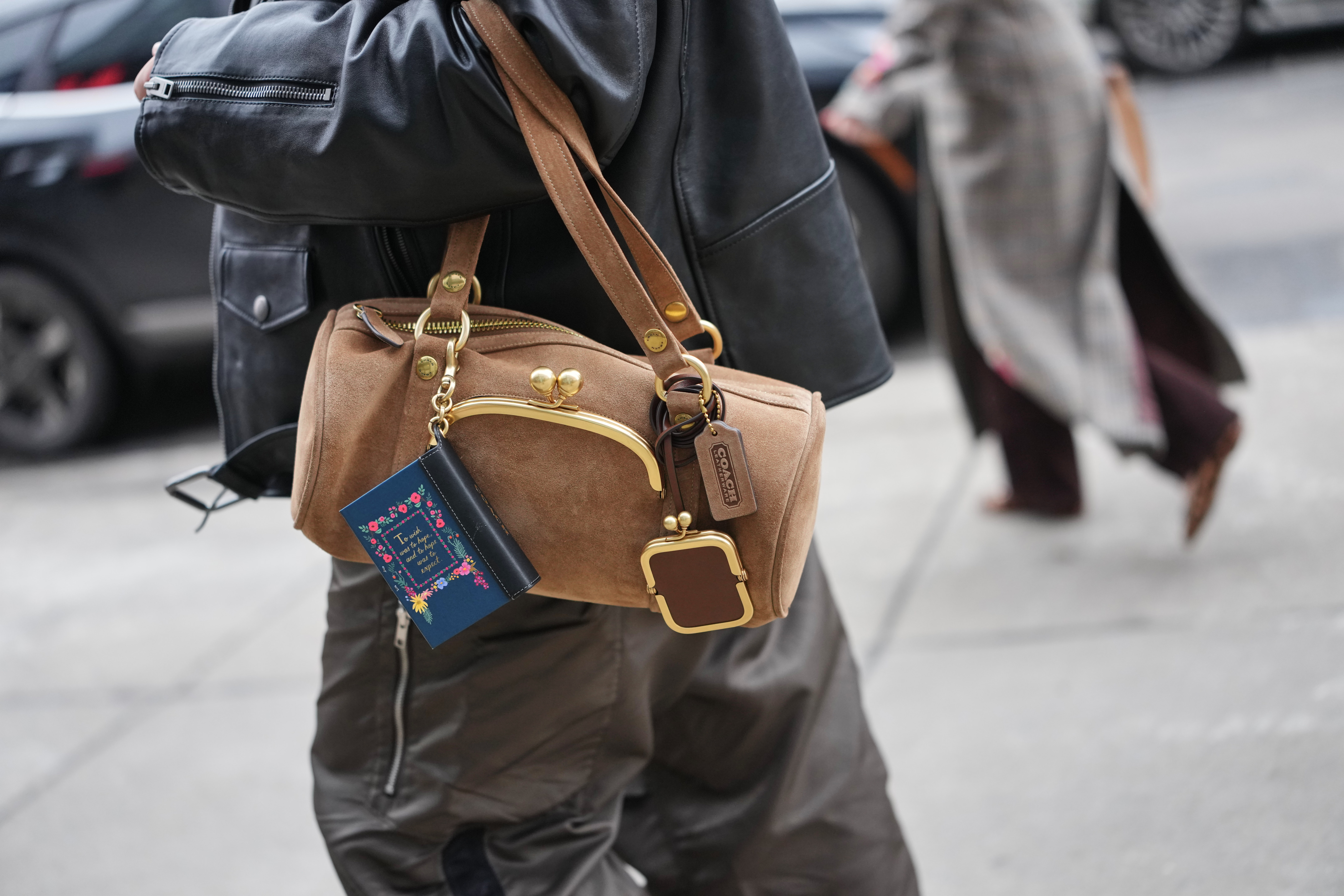 a guest at fashion week wearing a coach bag charm