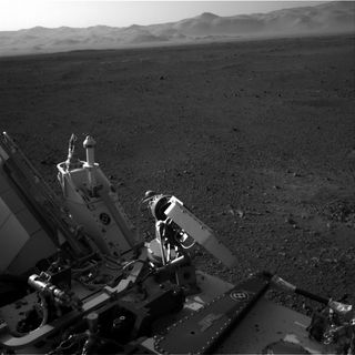 This view shows part of Curiosity rover at bottom with the rim of Gale Crater on Mars in the distance. Image released August 9, 2012.
