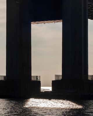 Large pillars under a bridge by the ocean.