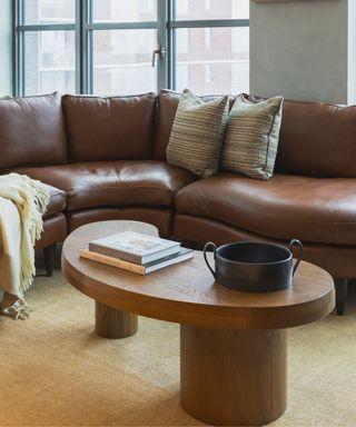 brown leather corner sofa with curved wooden coffee table and beige rug