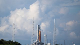 nasa space launch system giant rocket on launch pad with clouds in background sky