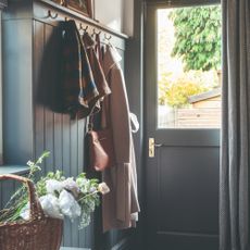 A hallway with panelled walls painted in navy blue with a matching front door