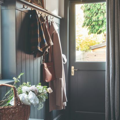 A hallway with panelled walls painted in navy blue with a matching front door