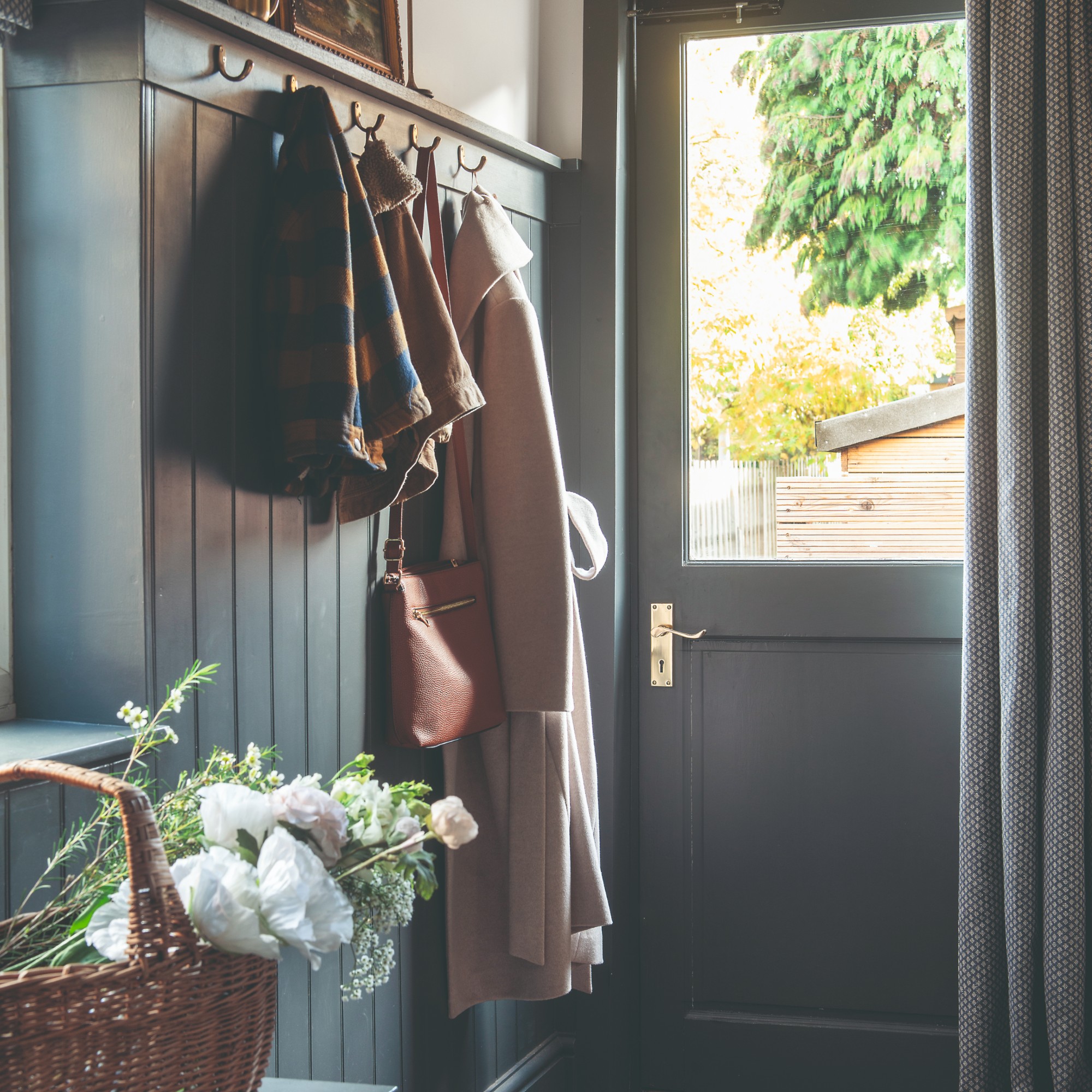 A hallway with panelled walls painted in navy blue with a matching front door