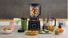 A Ninja blender surrounded by various things you can make with it like smoothies, and chopped fruit.