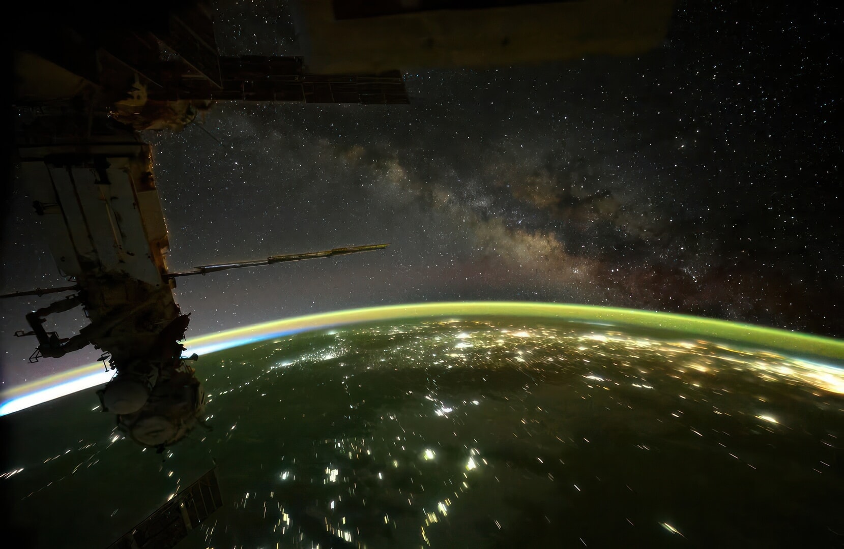 A photo of lights on Earth during nighttime taken from the ISS with the Milky Way visible in outer space