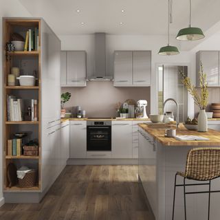 grey kitchen cabinets with grey kitchen island with wooden worktops and green pendant lights above, with wooden flooring