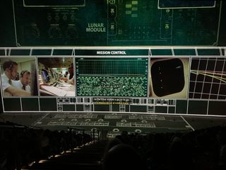 Projected images on a movie screen and the theater's floor recreate the look of Apollo mission control.