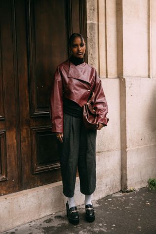 woman wearing leather jacket, trousers, socks, and loafers