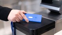 A stock photo of a hand holding a NFC card on a sensor, performing a security/id check