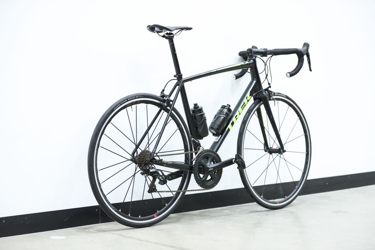 A black and yellow Trek Emonda ALR sits against a white wall
