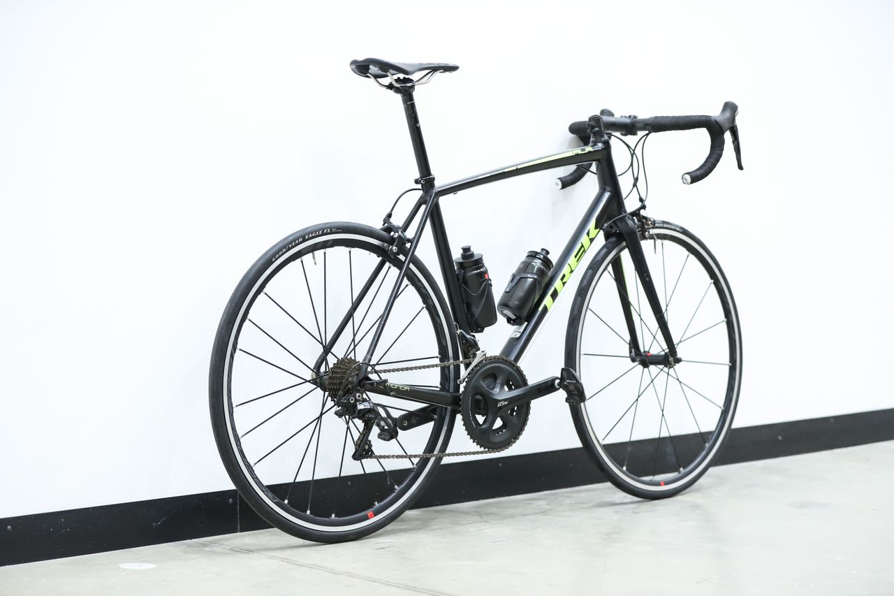 A black and yellow Trek Emonda ALR sits against a white wall