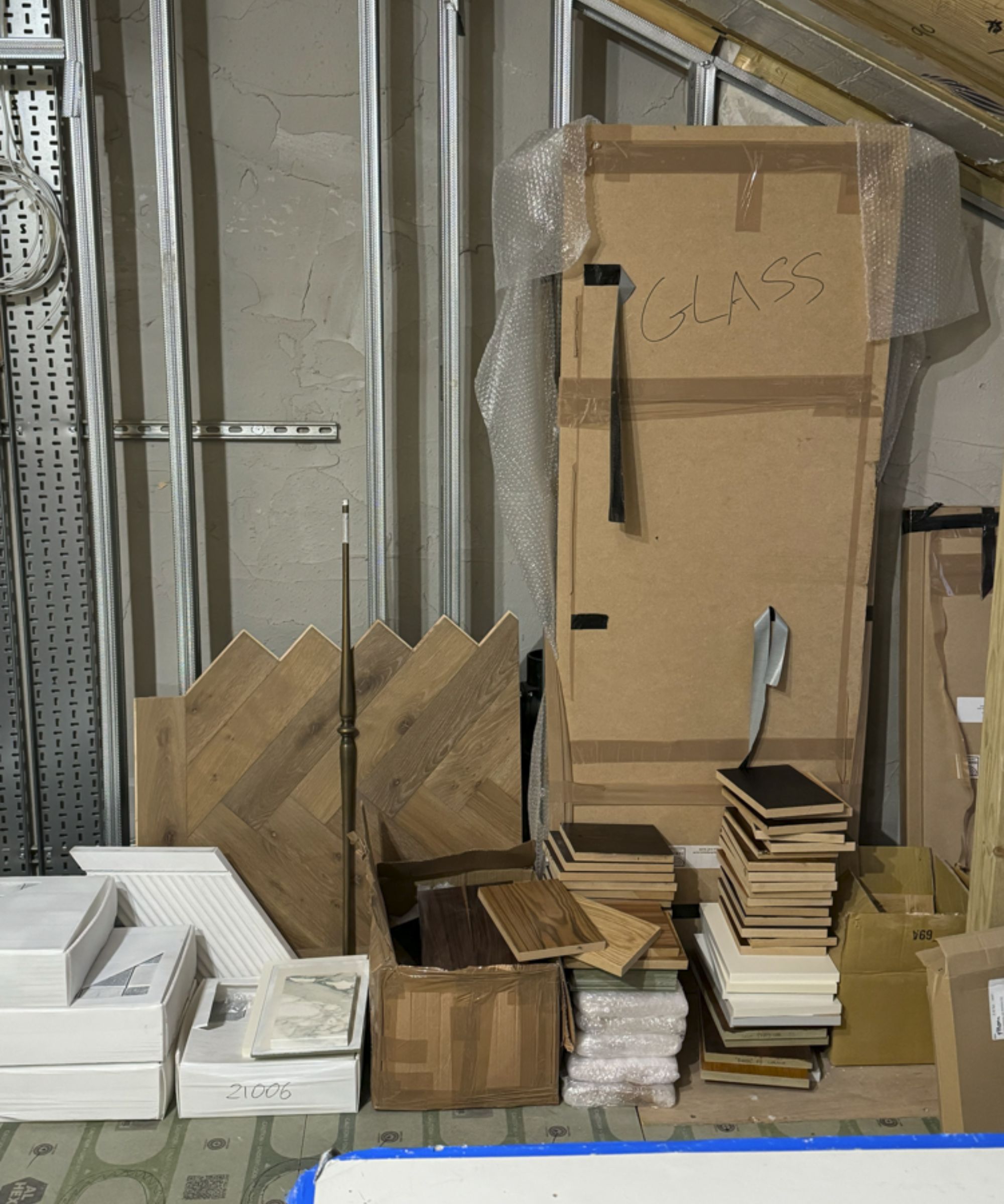 Image of stacked tiles, boxes and materials in a room undergoing construction