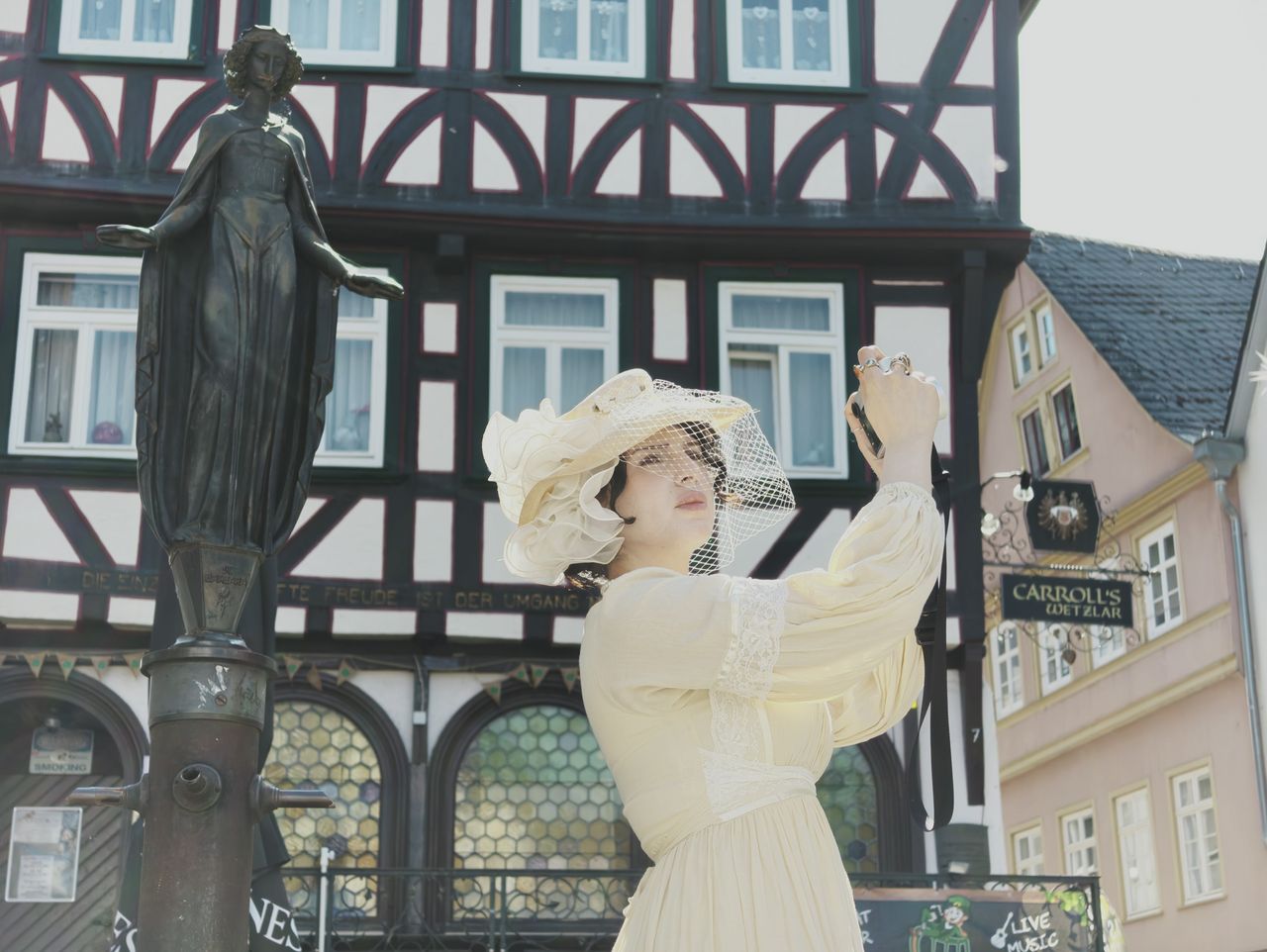 Insta360 Luna Ultra sample gallery: lady in period clothing holding a Leica camera, in quaint German town,