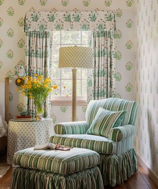 corner of room with green striped armchair and footstool, green and white patterned curtains and wallpaper