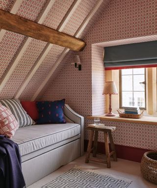 Attic room with beams, smallscale wallpaper and a sofa under the eaves