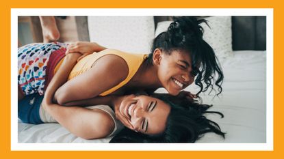 lesbian couple in bed laughing and hugging
