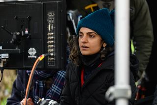 Nida Manzoor looks at a monitor on a film set