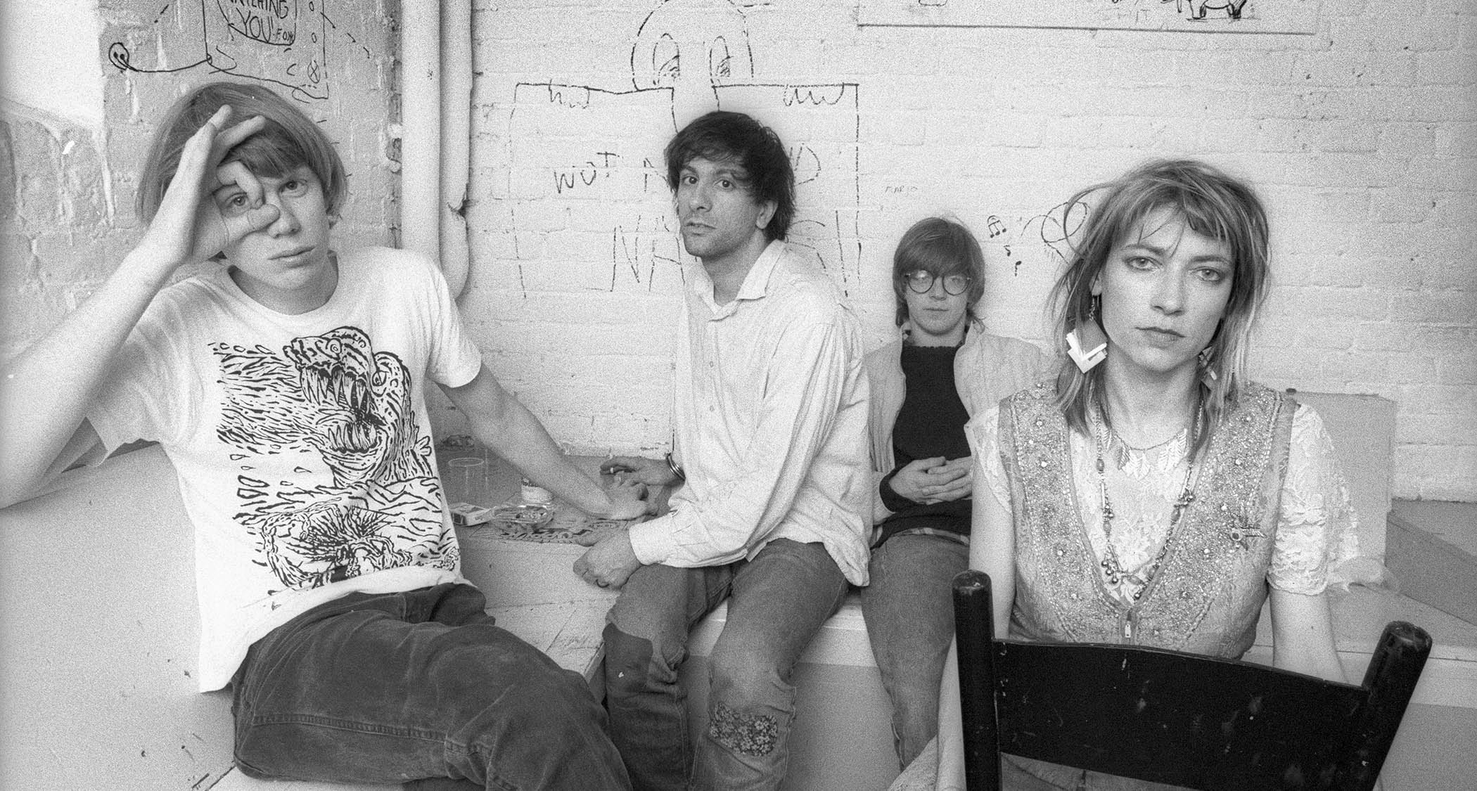 A black-and-white picture of Sonic Youth in 1986, pictured backstage [L-R]: Thurston Moore, Lee Ranaldo, Steve Shelley, Kim Gordon