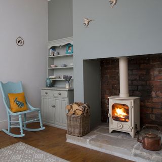 Cream lit log burner in a light blue room with blue chairs and furniture surrounding it