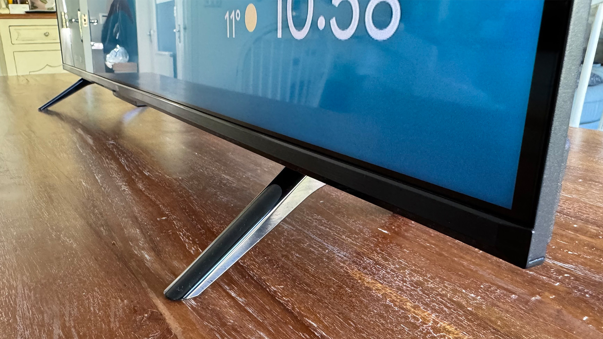 TCL P7K 43-inch TV on wooden table, detail of feet and bottom corner of set