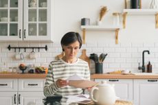 A woman sitting at her kitchen table reading a document