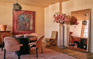 Dining room with light peach walls, terracotta accents and large floorstanding mirror