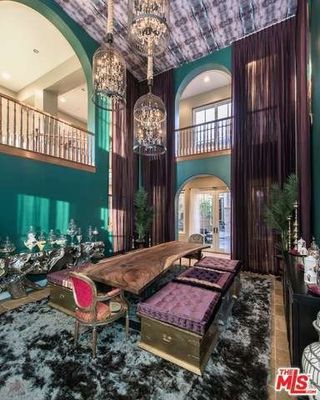 A double height dining room with a shag rug and purple drapes