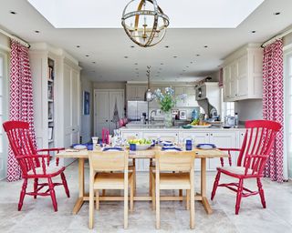 Stone kitchen flooring costs illustrated in an open plan neutral scheme with pops of red.