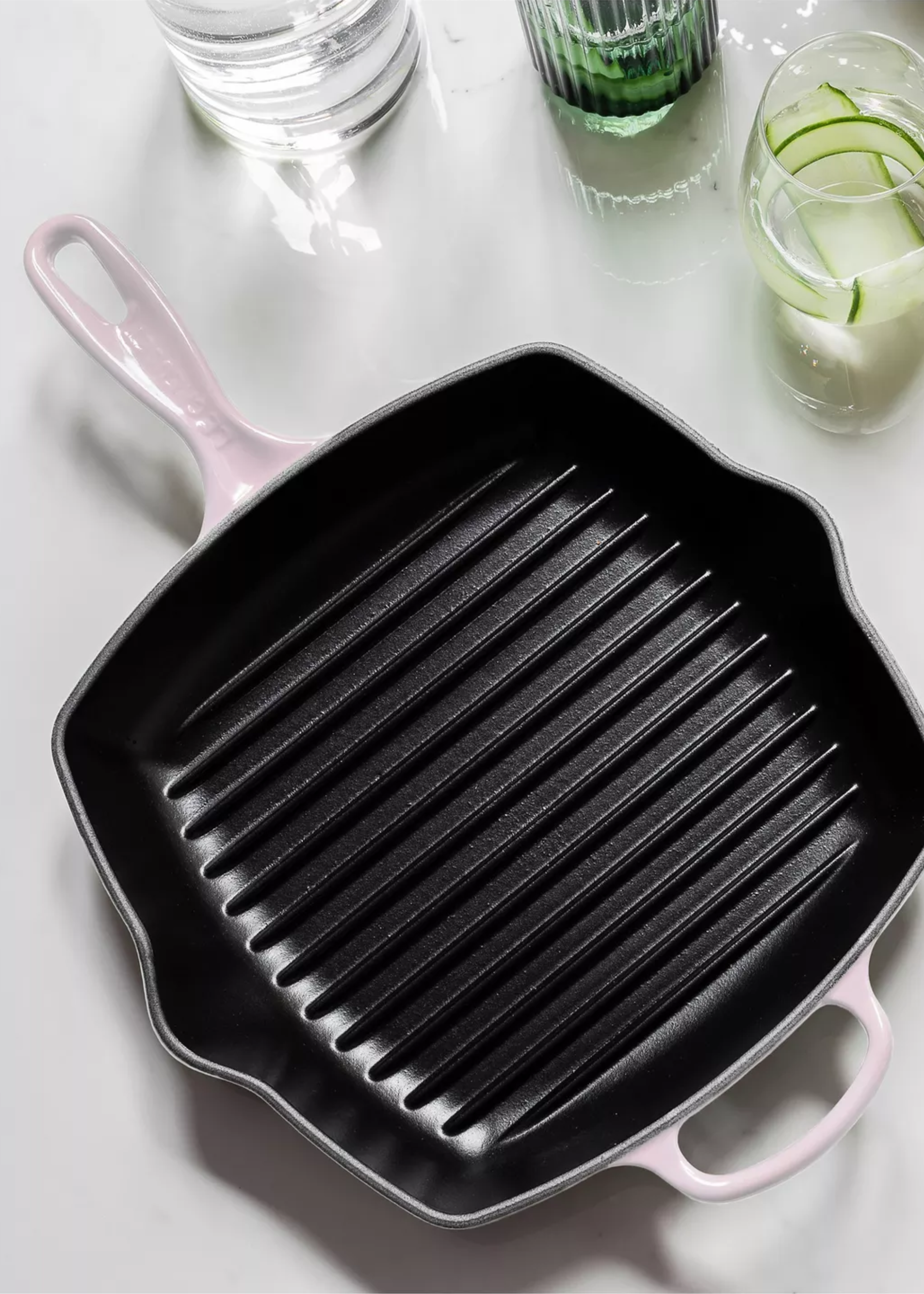A cast iron grill plan with a pale pink enamel coating