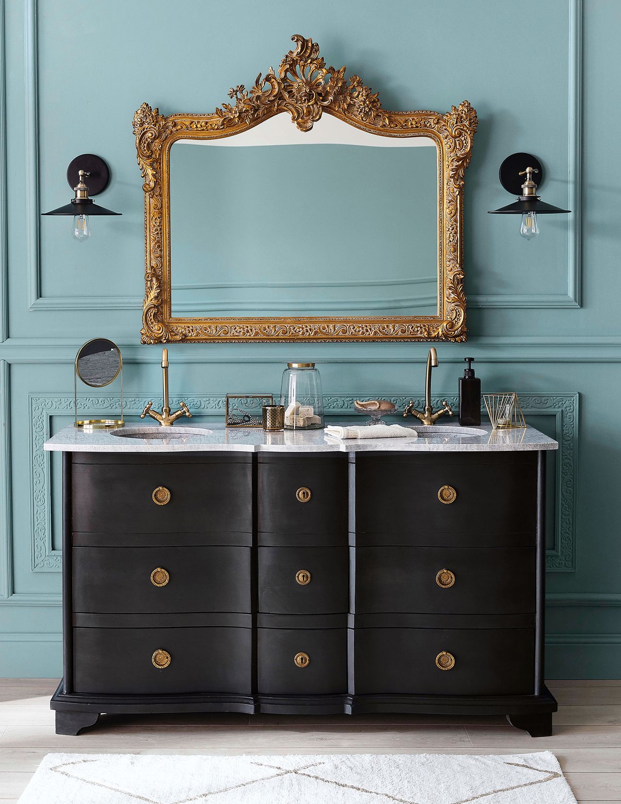 bathroom with stone countertop, orante mirror, wall lights and blue paneled wall