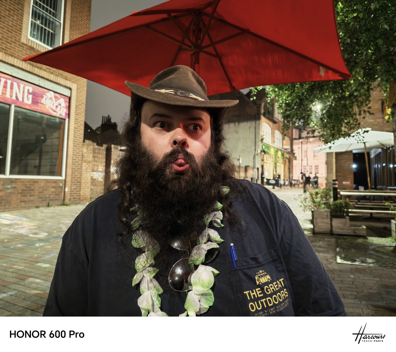 Night portrait of a bearded man in a hat under a red umbrella