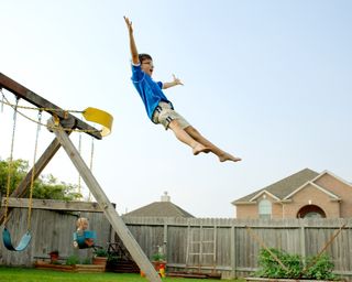 Boy jumps off swing in his backyard, Tomball, Texas