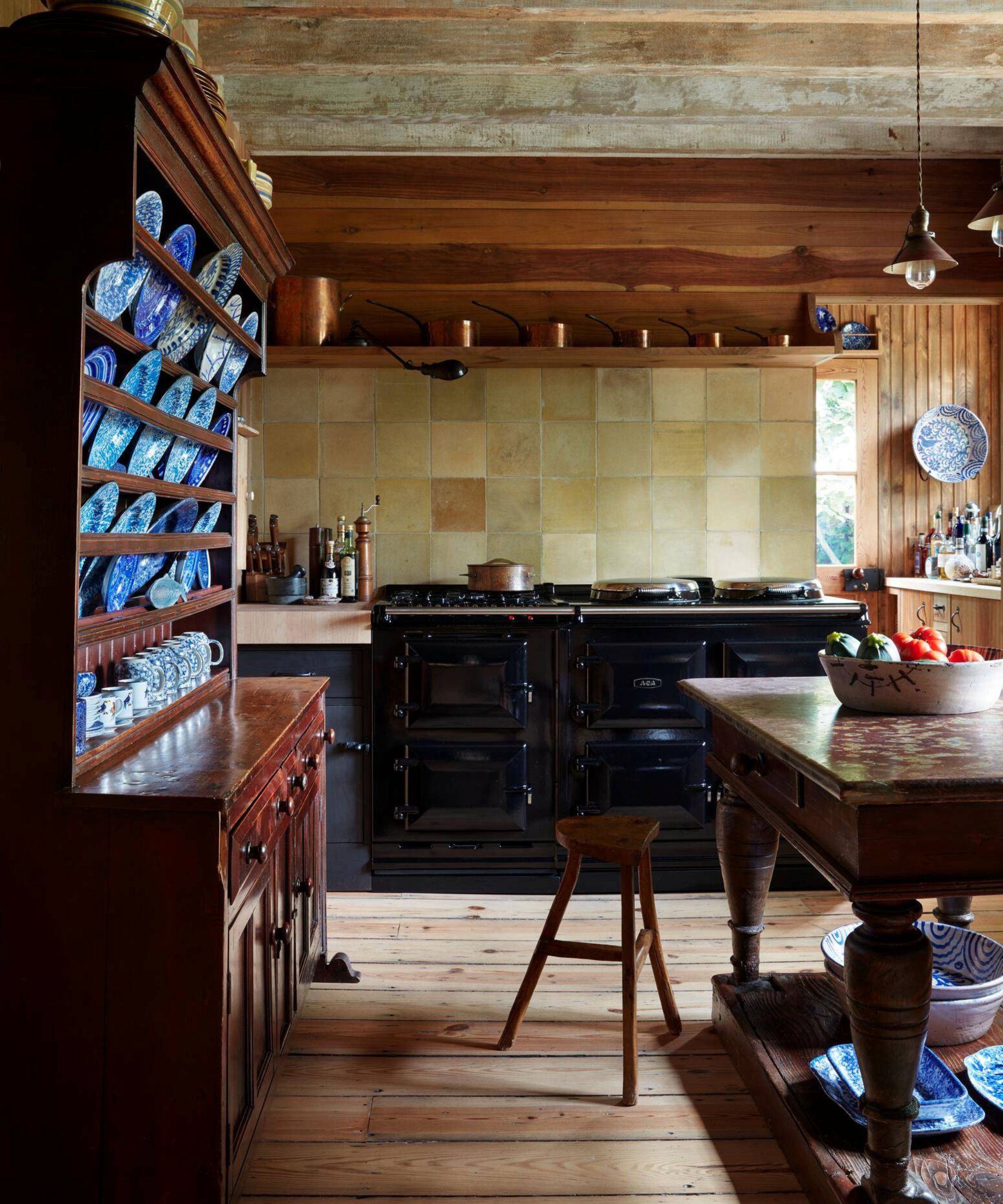 a cedar clad kitchen in Long Island with an antique range cooker, kitchen table and credenza