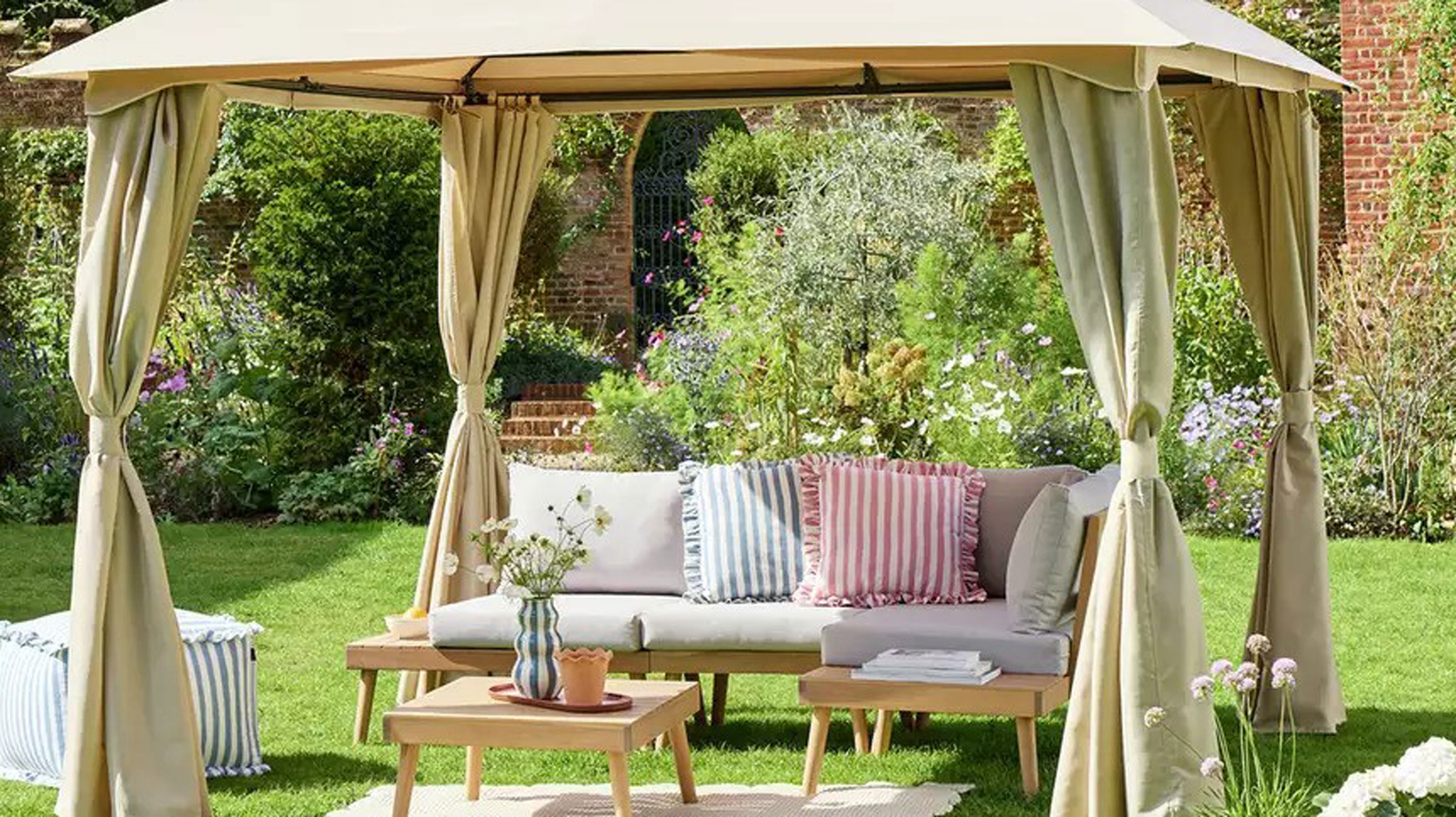 Beige gazebo on a lawn over a corner sofa with an outdoor rug and coffee table