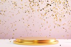 Two-tier round gold metal podium on pastel pink background with many falling gold confetti. Perfect platform for showing your products. 