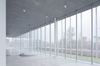 Interior of the museum with pale grey tones and full-height windows
