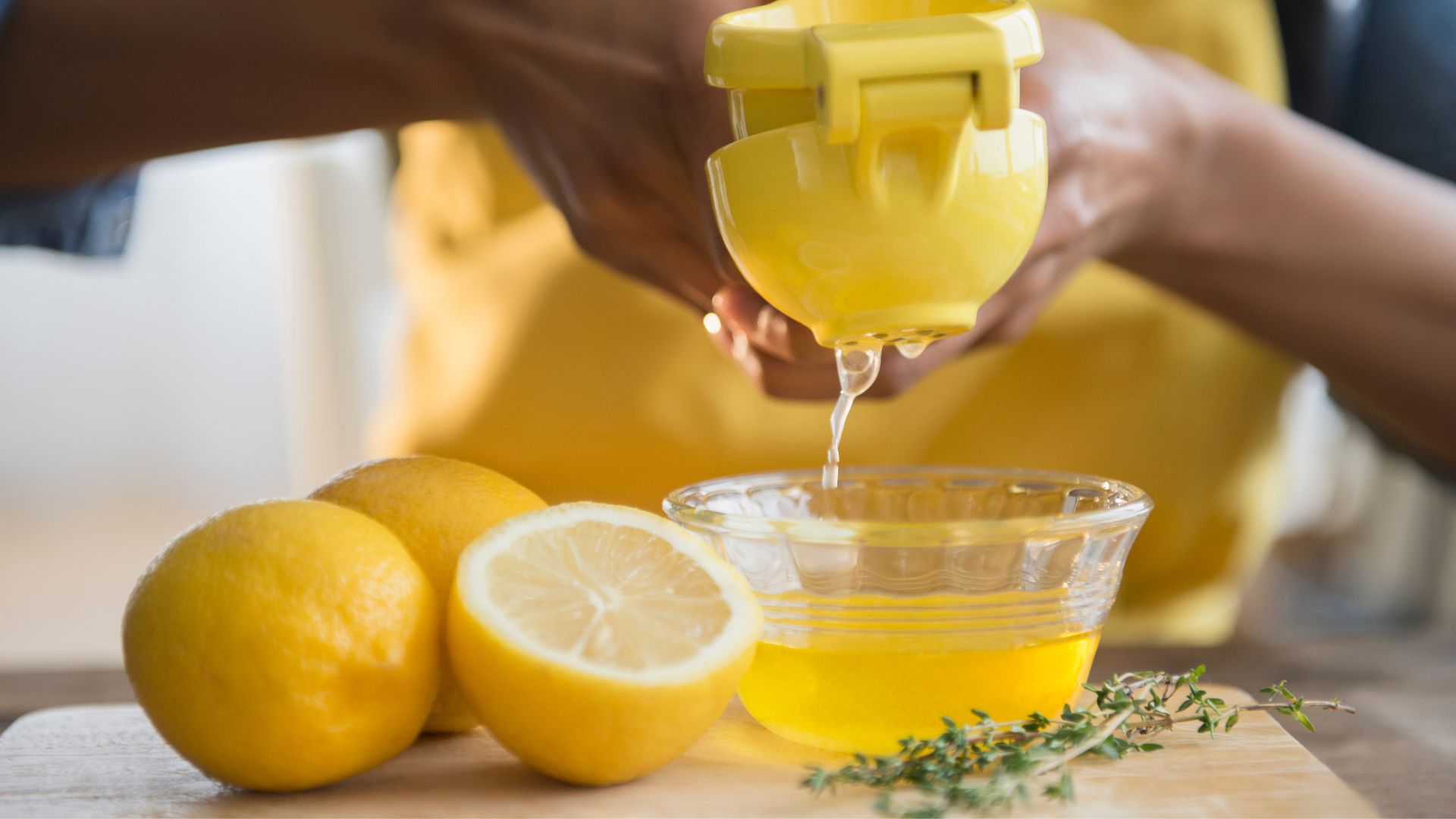 person squeezing fresh lemons into bowl