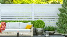 garden sofa on a decked patio in front of a white painted fence