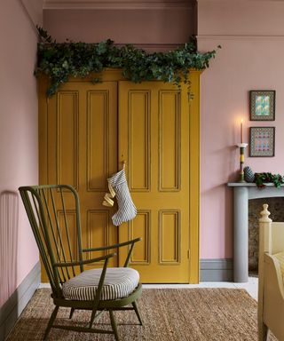 bedroom with pink walls, mustard yellow built-in wardrobe with green Christmas wreath attached to the top