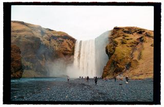 A large waterfall in Iceland with people gathered around the bottom