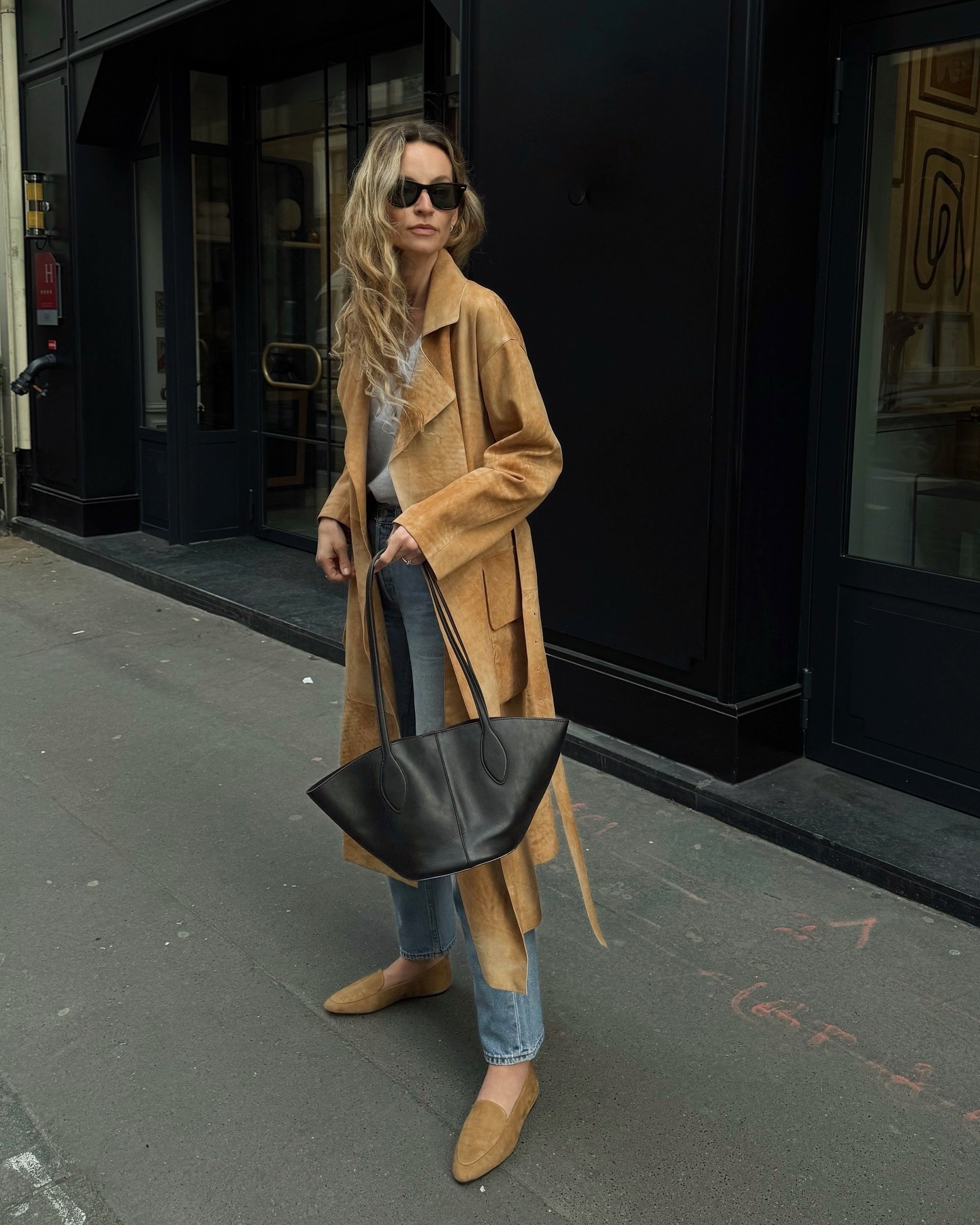 Woman wears suede trench coat, blue jeans and suede flats