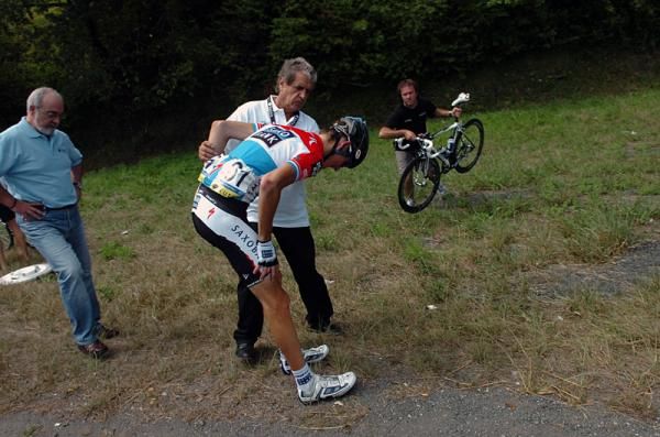 Andy Schleck assesses his injuries following a crash while his bike is retrieved by a mechanic.