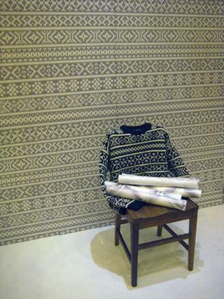 Print jumper on a brown wooden chair photographed against a wall with matching print wall paper