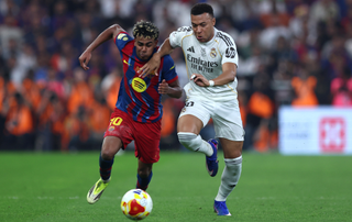Kylian Mbappe of Real Madrid battles for possession with Lamine Yamal of FC Barcelona
