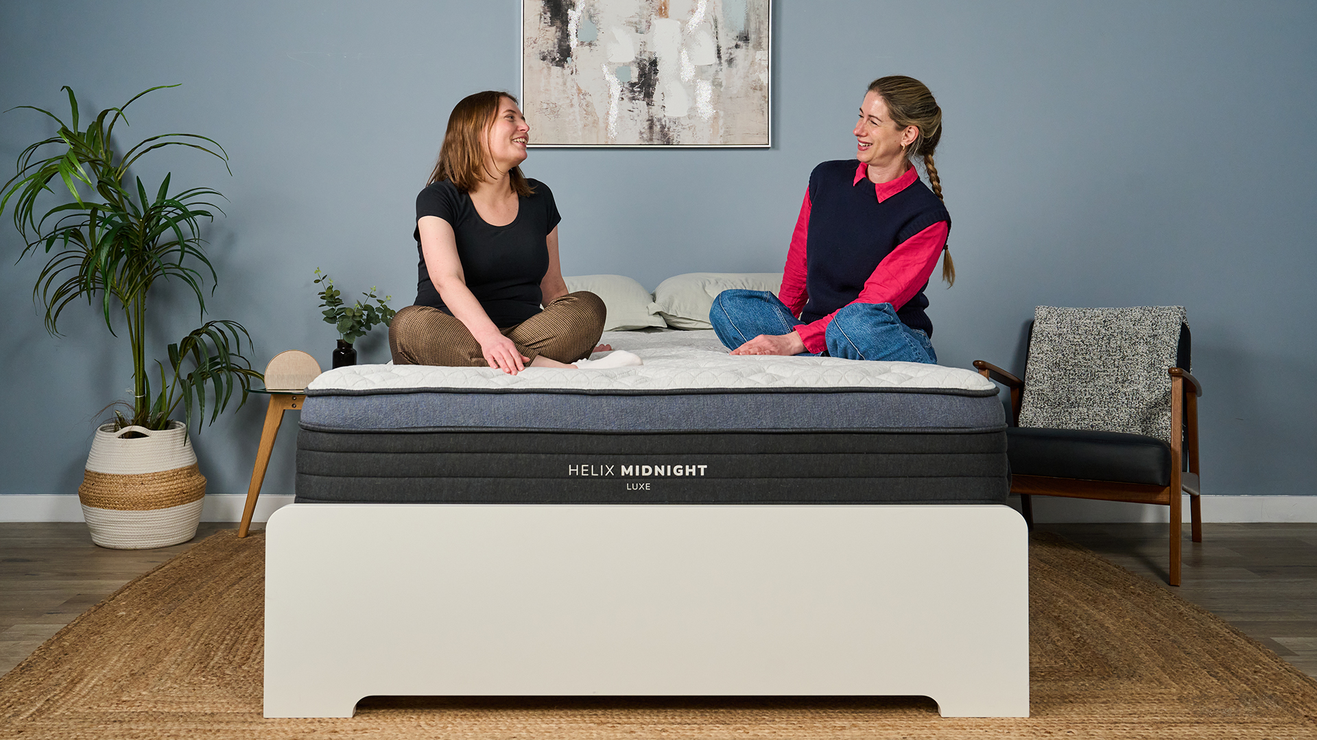 Testers Ruth Jones and Nicola Appleton sit on the Helix Midnight Luxe mattress in the sleep studio, discussing the comfort and firmness.