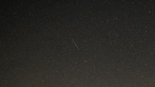 a streak of light against a starry night sky