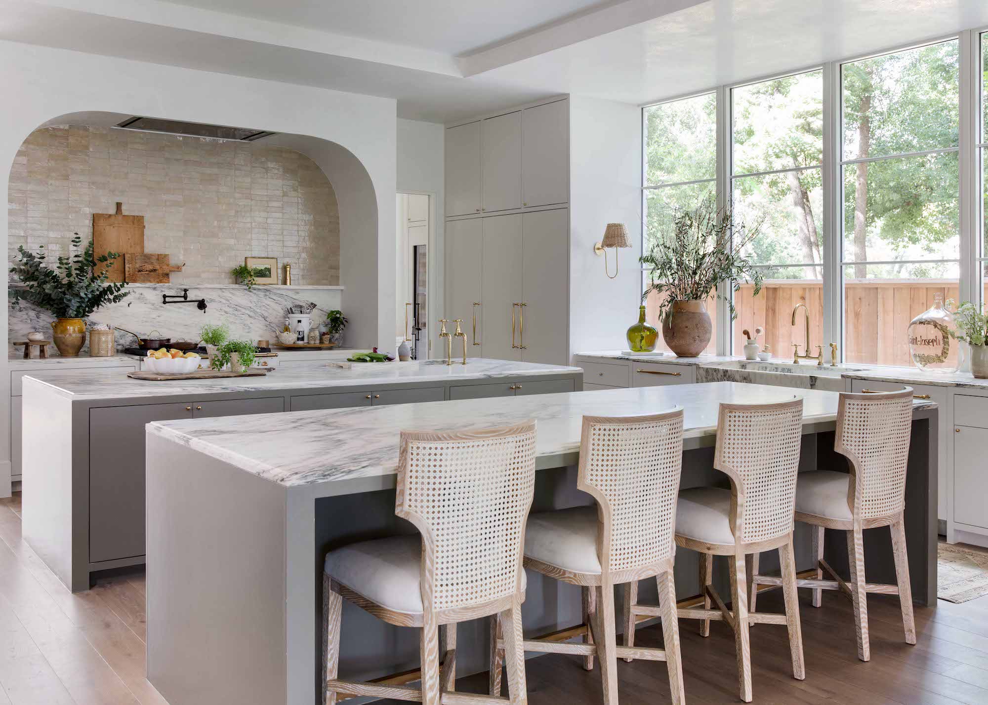 two marble topped islands. One of the islands have bar stools beside them while the other has extra storage and kitchen essentials placed on top.