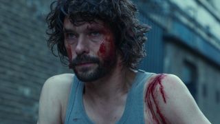 A bloodied Ben Whishaw crouches in an alley looking upset in Black Doves.